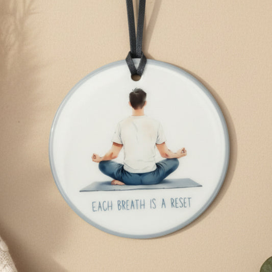 Necklace with a pendant featuring a person meditating on a mat and the text 'Each breath is a reset' against a light background.