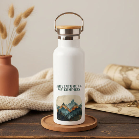 White water bottle with 'Adventure is My Compass' design on a wooden surface with decorative elements.
