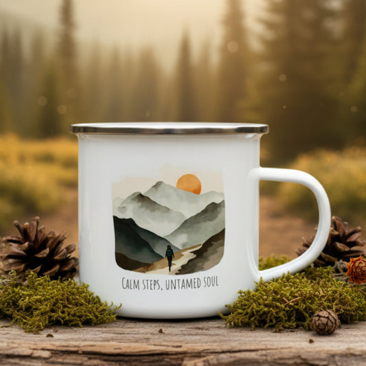 Enamel mug with mountain design and text on a wooden surface