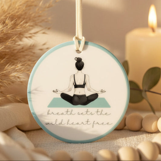 Decorative hanging disc with a meditating figure and text on a light background