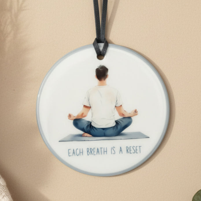 Necklace with a pendant featuring a person meditating on a mat and the text 'Each breath is a reset' against a light background.