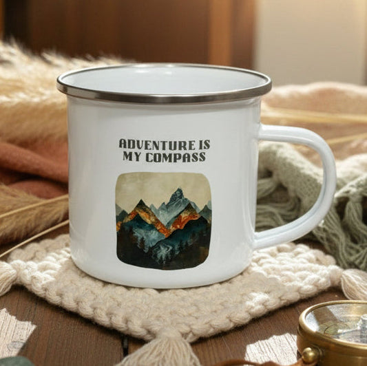White mug with 'Adventure is my compass' text and mountain graphic on a wooden table.