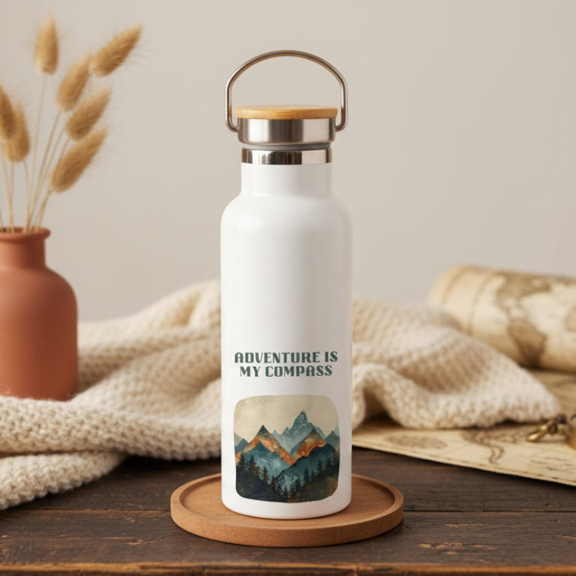 White water bottle with 'Adventure is My Compass' design on a wooden surface with decorative elements.