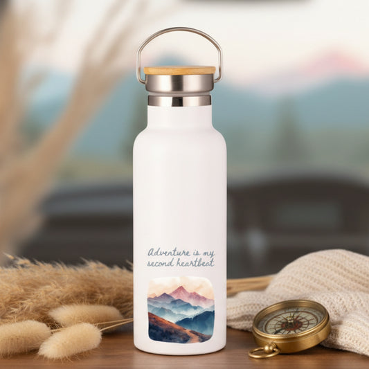 White water bottle with mountain design and 'Adventure is my second heartbeat' text on a dashboard with a blurred outdoor background.