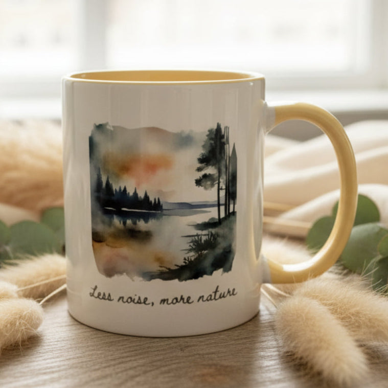 Mug with a nature-themed design and 'less noise, more nature' text on a blurred background
