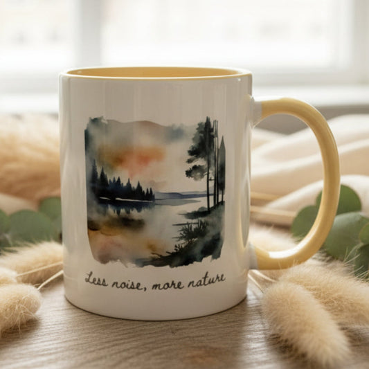 Mug with a nature-themed design and 'less noise, more nature' text on a blurred background
