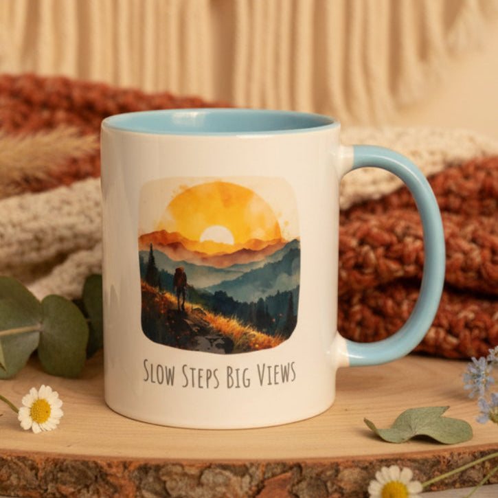 Mug with a scenic design and 'Slow Steps Big Views' text on a white surface.
