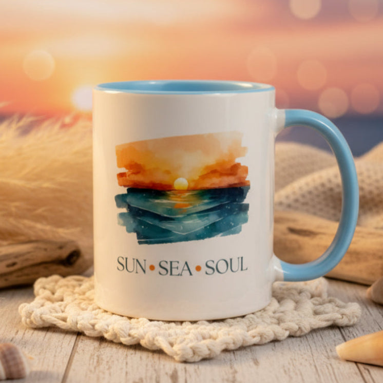 Mug with a colorful design and 'Sun Sea Soul' text on a white surface with plants in the background