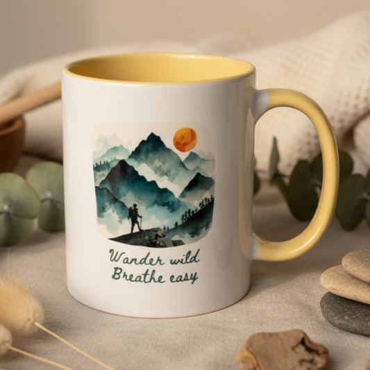 Mug with mountain design and text 'Wander wild, Breathe easy' on a plain background